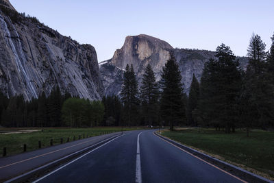 Road amidst trees and mountains against sky