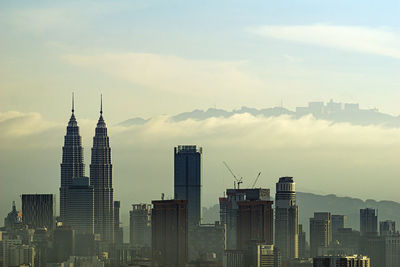 Modern buildings in city against cloudy sky