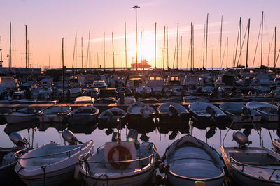 Sailboats moored at harbor during sunset