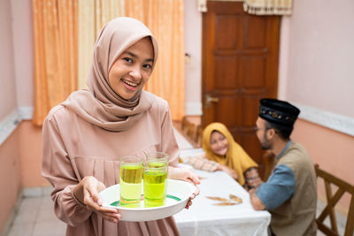 Portrait of smiling woman holding drinks at home