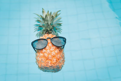 Sunglasses on pineapple floating in swimming pool