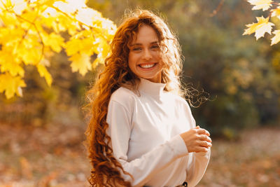 Portrait of young woman standing against plants