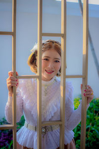 Portrait of smiling woman seen through metal grate