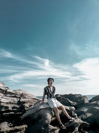 Man on rock against sky