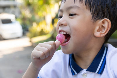 Close-up of boy eating lollipop on footpath