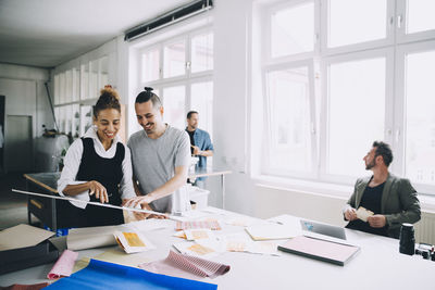 Smiling male and female professionals discussing at table in creative office