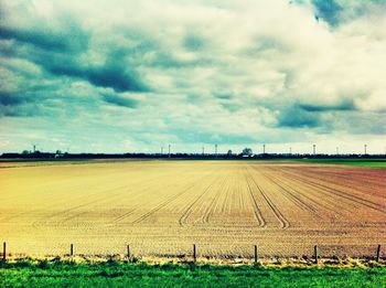 Scenic view of field against cloudy sky