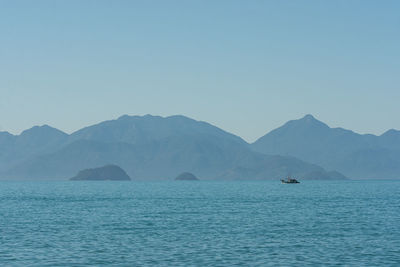 Scenic view of sea and mountains against clear sky