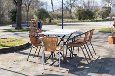 Wicker stack chairs or garden chairs at an outdoor table in sunny weather