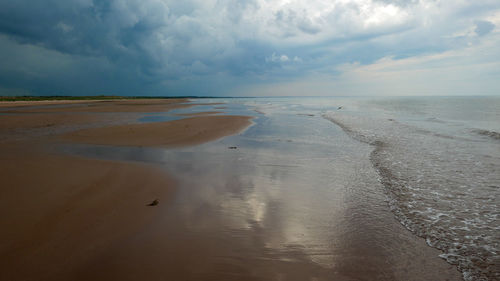 Scenic view of beach against sky with relections and waves