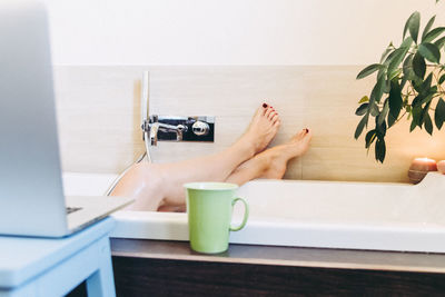 Low section of woman relaxing in bathtub 
