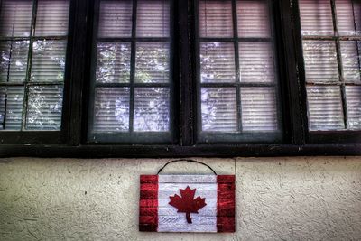 Canadian flag painted on wooden board mounted to wall