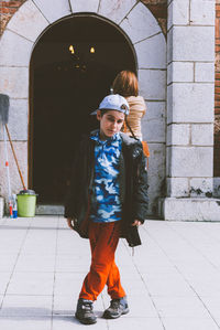 Portrait of boy standing against building