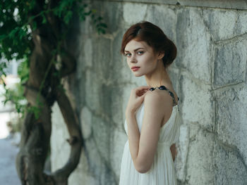 Portrait of woman standing against wall