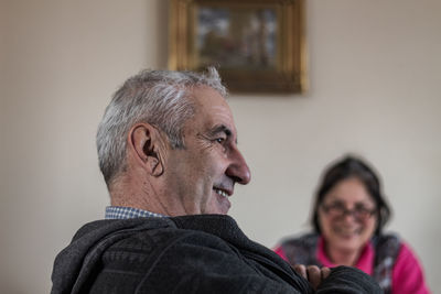 Side view of smiling senior man looking away at home