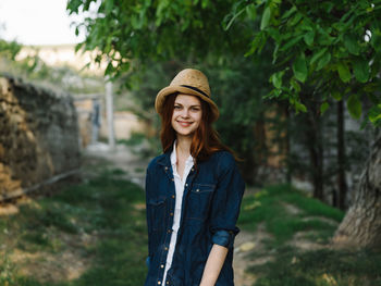 Portrait of smiling young woman standing against plants