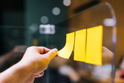 Cropped image of person holding adhesive notes against blurred background