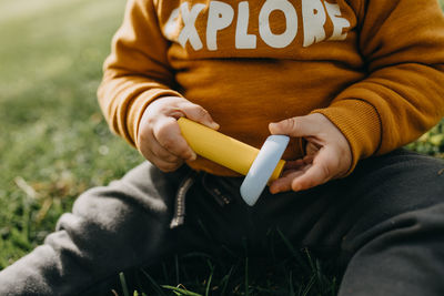 Midsection of man holding mobile phone sitting on grass