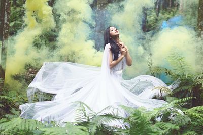 Woman with arms outstretched standing against plants