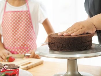 Midsection of female friends preparing cake at table