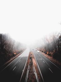 Road amidst trees against sky during foggy weather