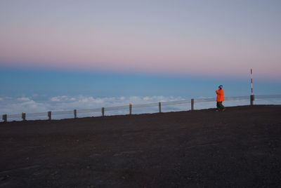 Man standing on beach against sky during sunset