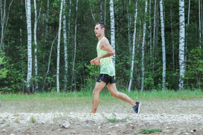 Full length of shirtless man running in forest