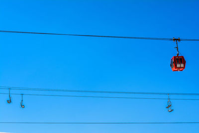 Low angle view of power lines against clear blue sky