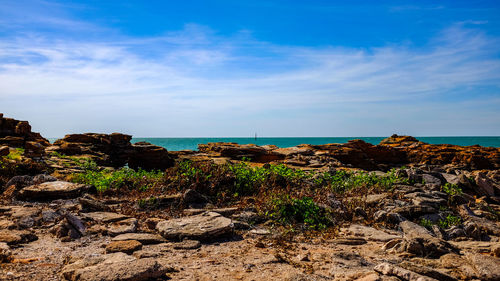 Scenic view of sea and rocks against blue sky