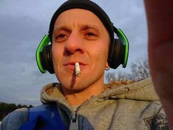 Low angle portrait of mid adult man smoking cigarette against sky