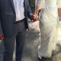 Low section of bride and groom holding hands while standing on street
