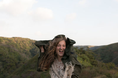 Smiling young woman standing against sky