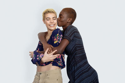 Woman kissing girlfriend against white background