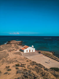 Scenic view of beach by sea against clear blue sky