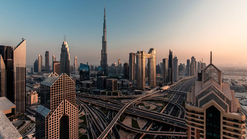 Modern buildings in city against sky during sunset