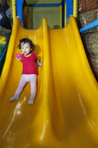 Full length of cute baby girl on yellow slide