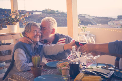 Senior loving couple toasting drinks with friends at restaurant