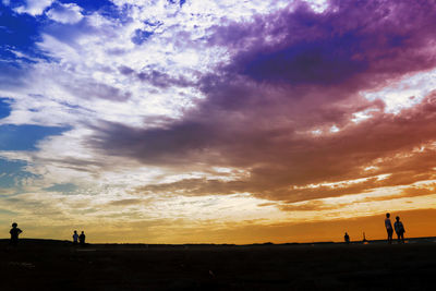 Silhouette people on beach against sky during sunset