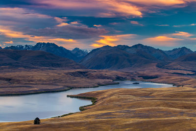 Scenic view of lake by mountains against sky during sunset