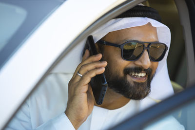 Close-up of man wearing traditional clothing talking mobile phone in car