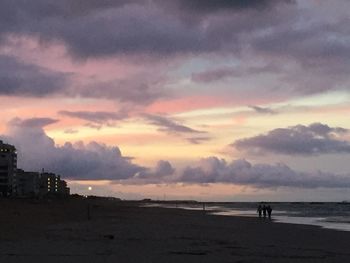 Scenic view of beach against sky at sunset