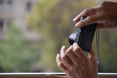 Cropped hands of man holding camera