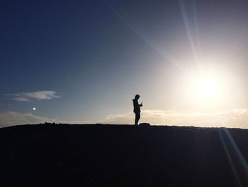 Silhouette man standing on landscape against sky during sunset