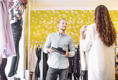 Smiling sales person looking at female customer in clothing store