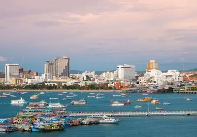 Boats in sea by buildings against sky in city
