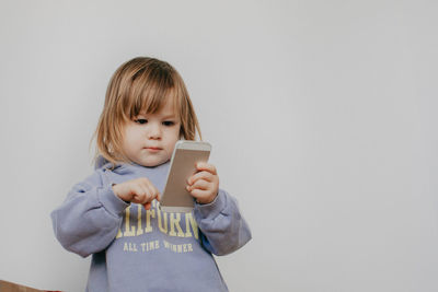 Portrait of young woman using mobile phone against wall