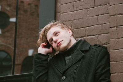 Young man wearing warm clothing while looking away against wall