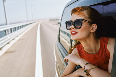 Young woman wearing sunglasses sitting in car
