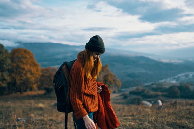 Rear view of man standing on mountain against sky