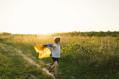 Ukrainian child boy in white t shirt with yellow and blue flag of ukraine in field.